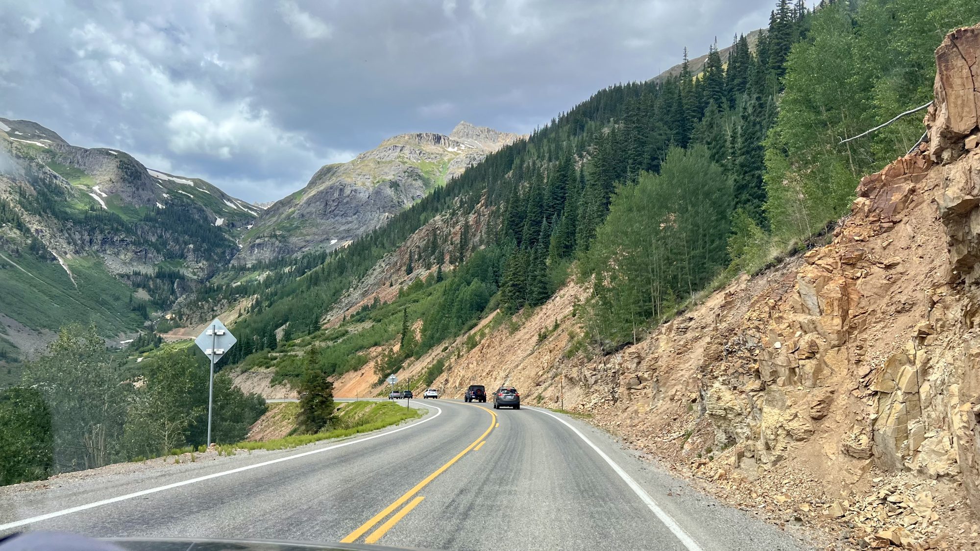 A winding two-lane mountain road between steep forested slopes