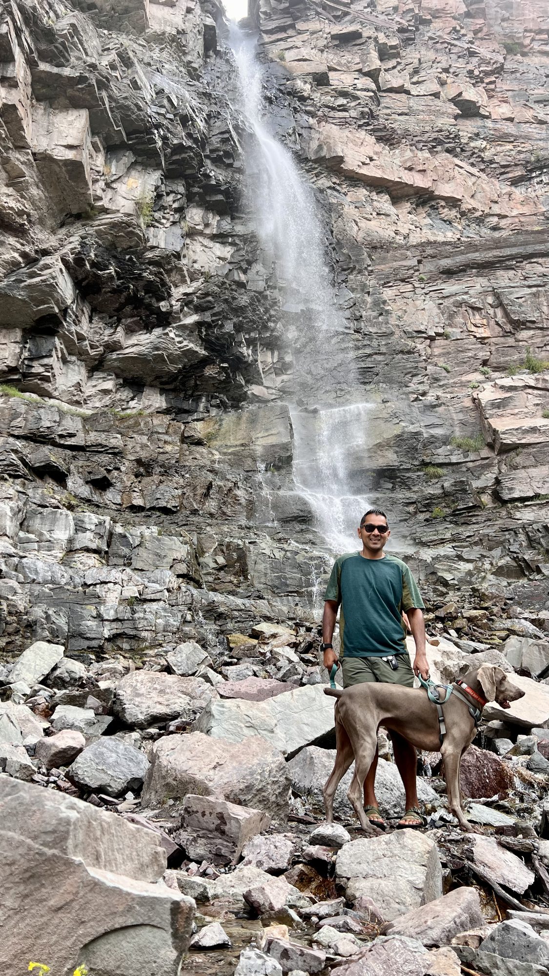 Man and dog on the rocks at the foot of Cascade Falls in Ouray