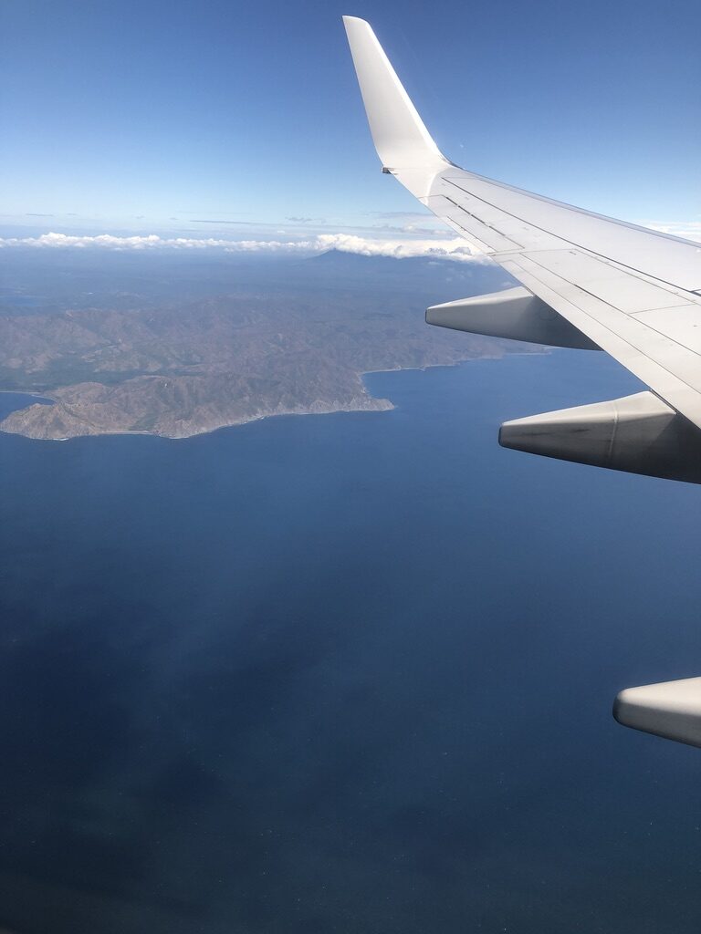 The Costa Rican coast seen from an airplane window, with the wing in view