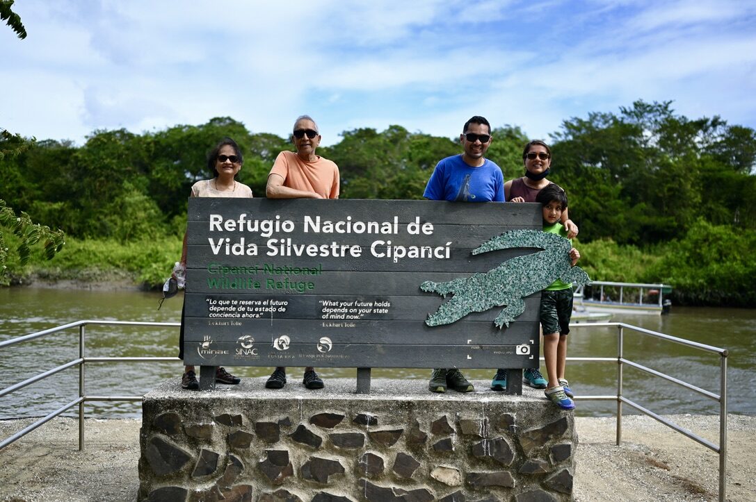 The family posing with the sign for the Cipancí wildlife refuge by the river