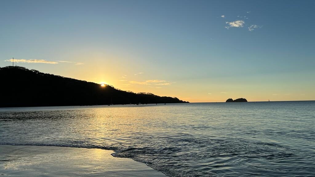 The sun setting behind a headland over the sea