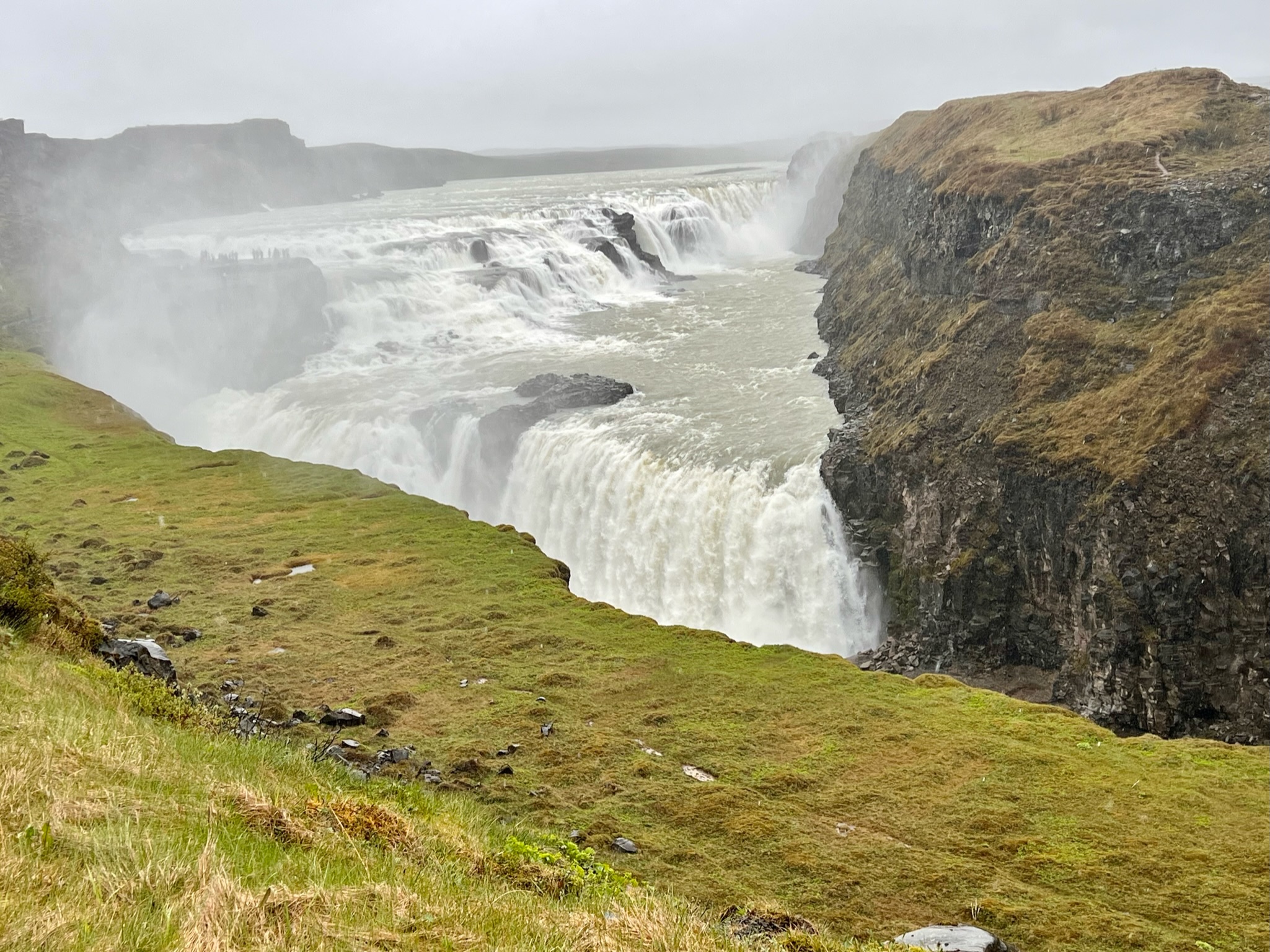View of Gullfoss waterfall in Iceland, with foreground of moss and grass covered cliff
