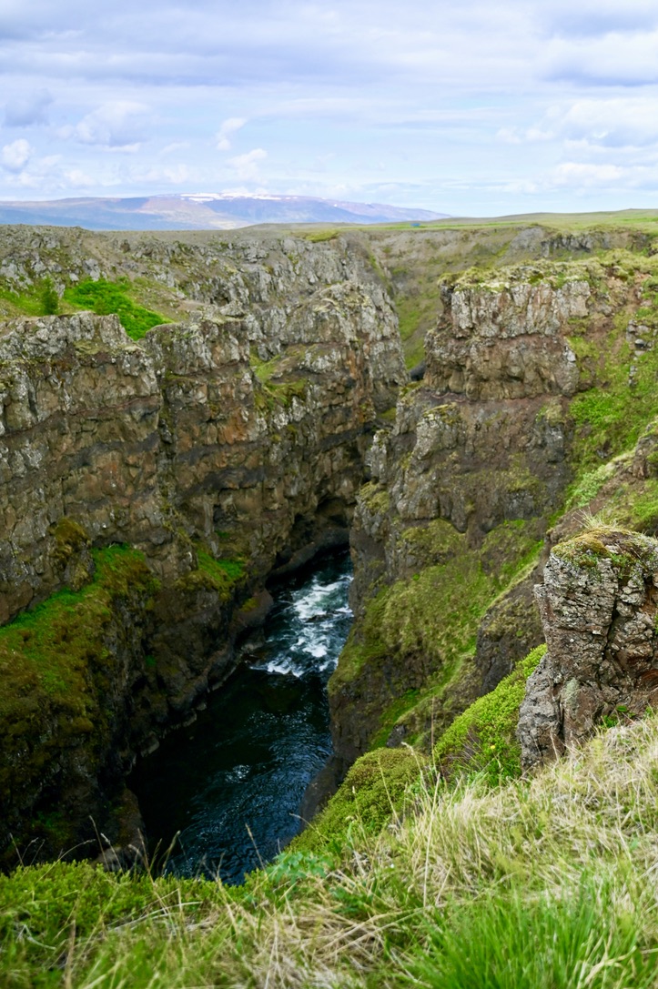 Rugged Kolugljufur canyon with rocky walls covered by moss and grass, and the river running through them