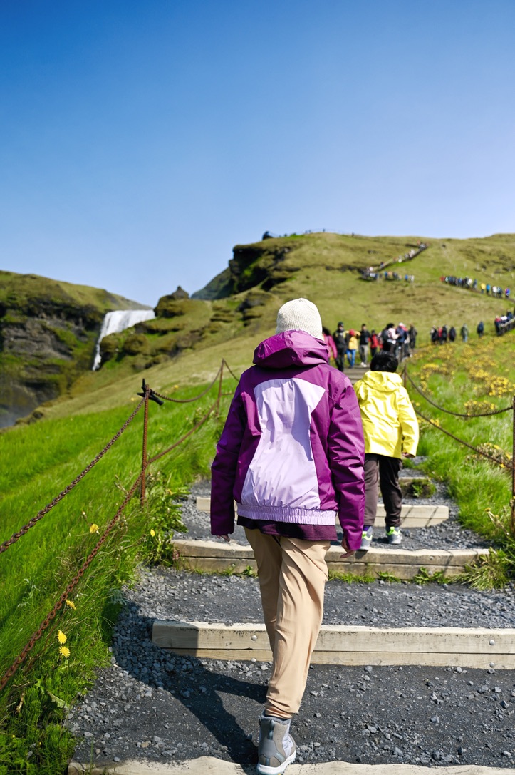 People walking up the stairs up the side of the hill by the Skogafoss waterfall in Iceland