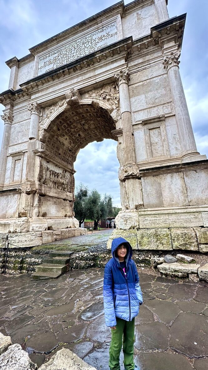 Boy standing beneath the Arch of Titus at the entrance to the Roman Forum