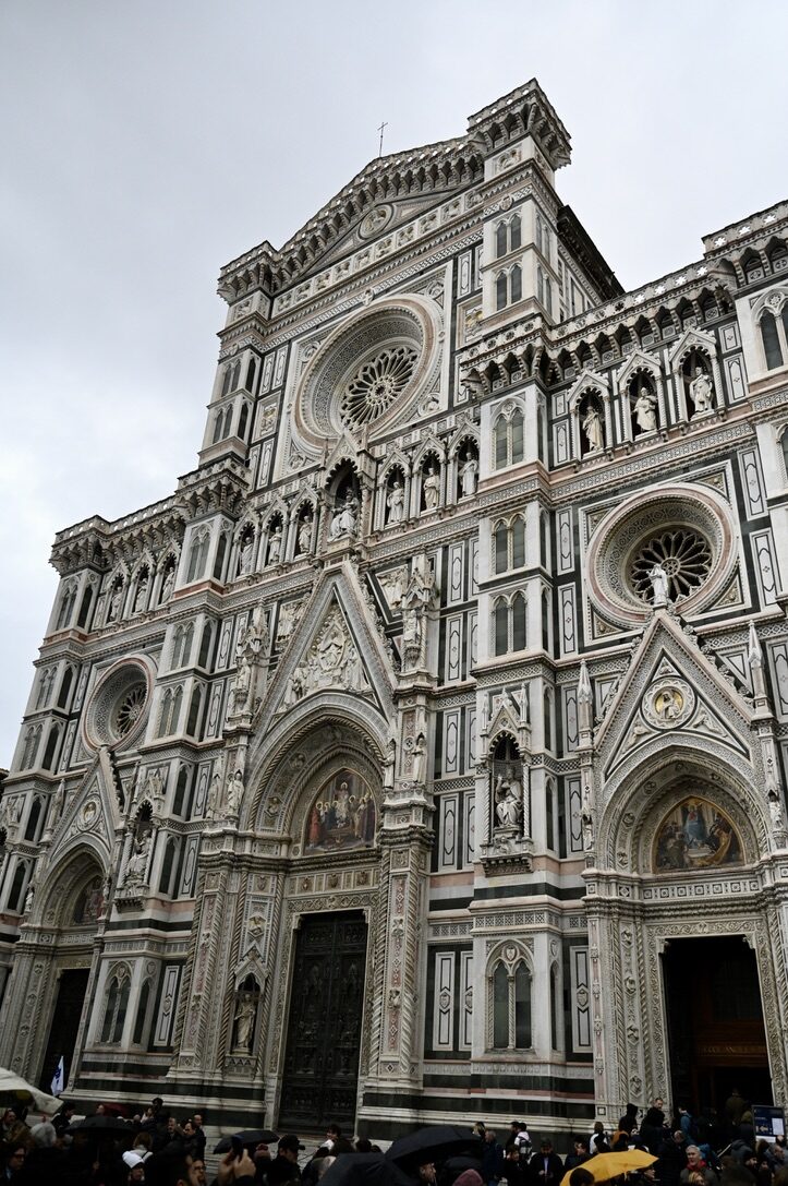 The marble facade of Florence’s Duomo against a gray sky