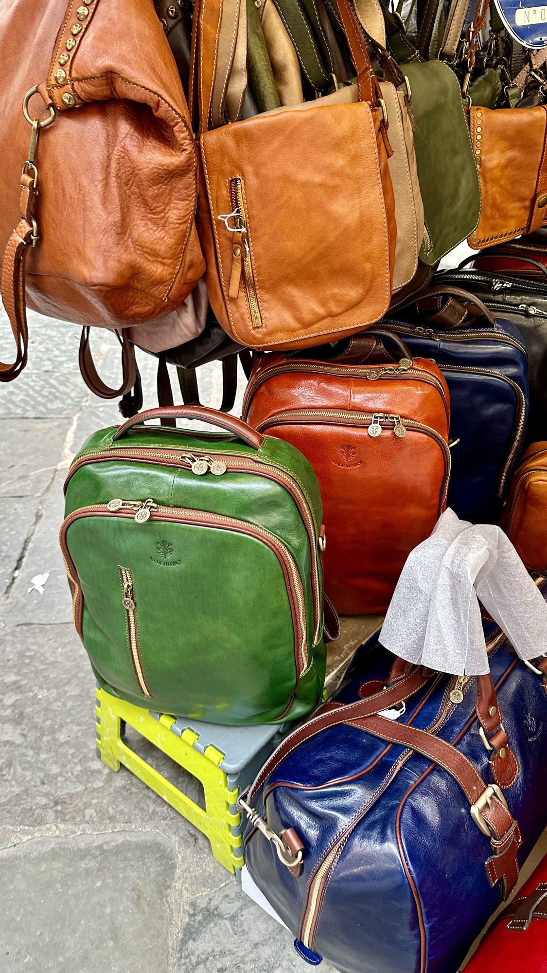 Colorful leather bags and backpacks hanging at a market stall