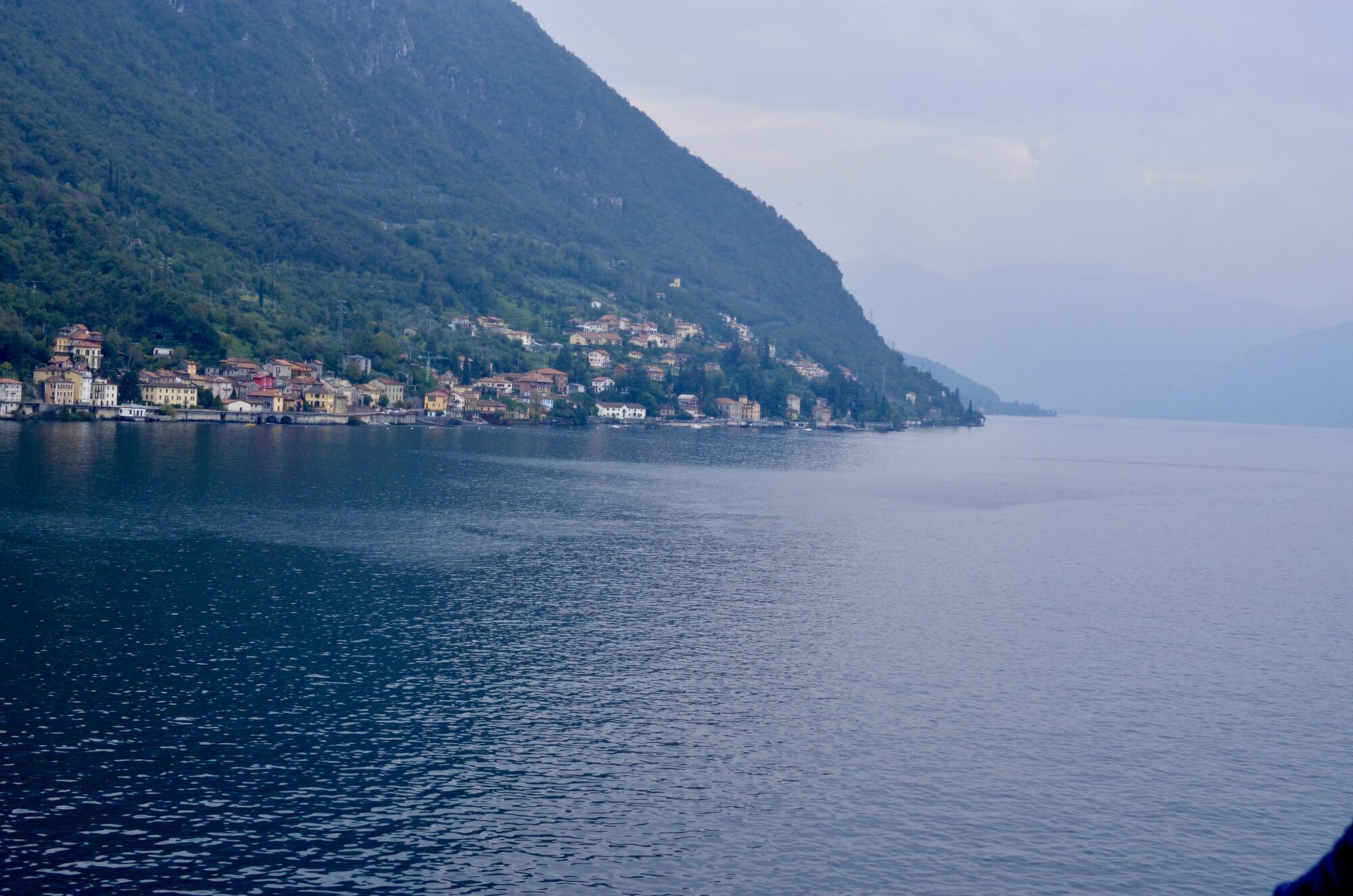 A lakeside village beneath steep green mountains on Lake Como