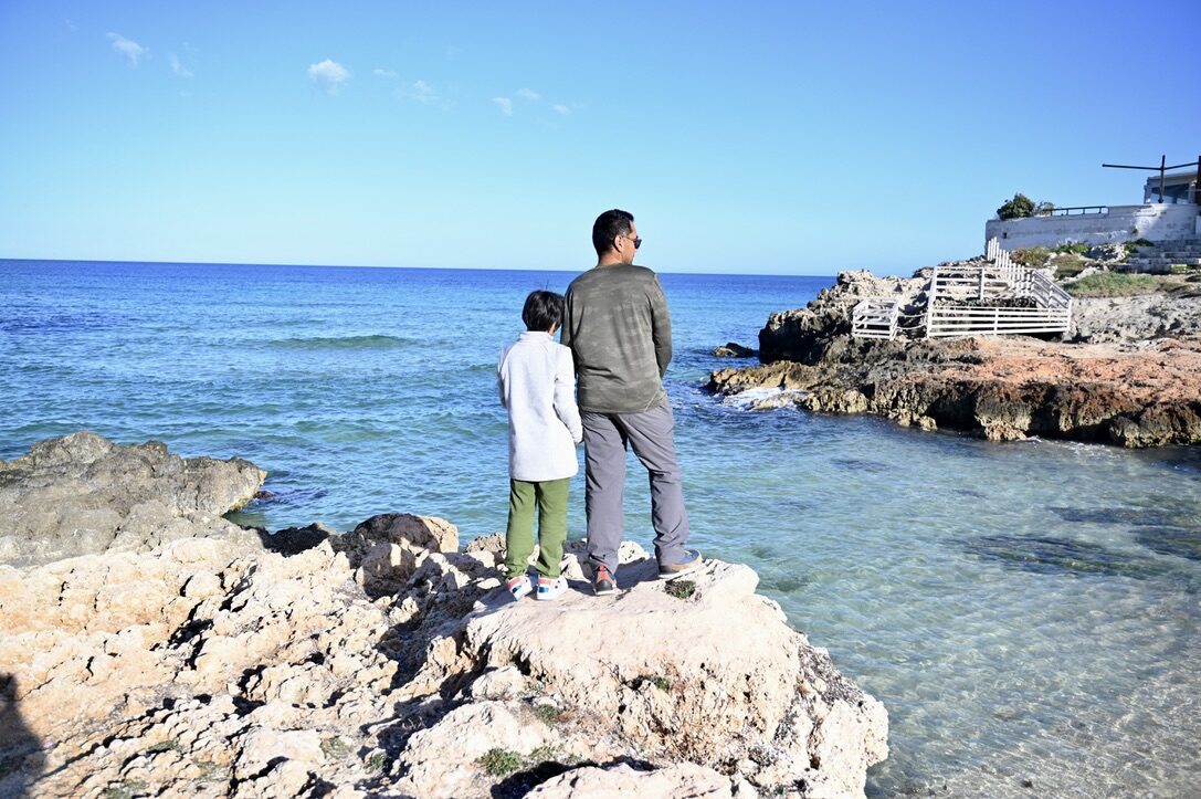 Man and boy standing on the rocks looking out to sea