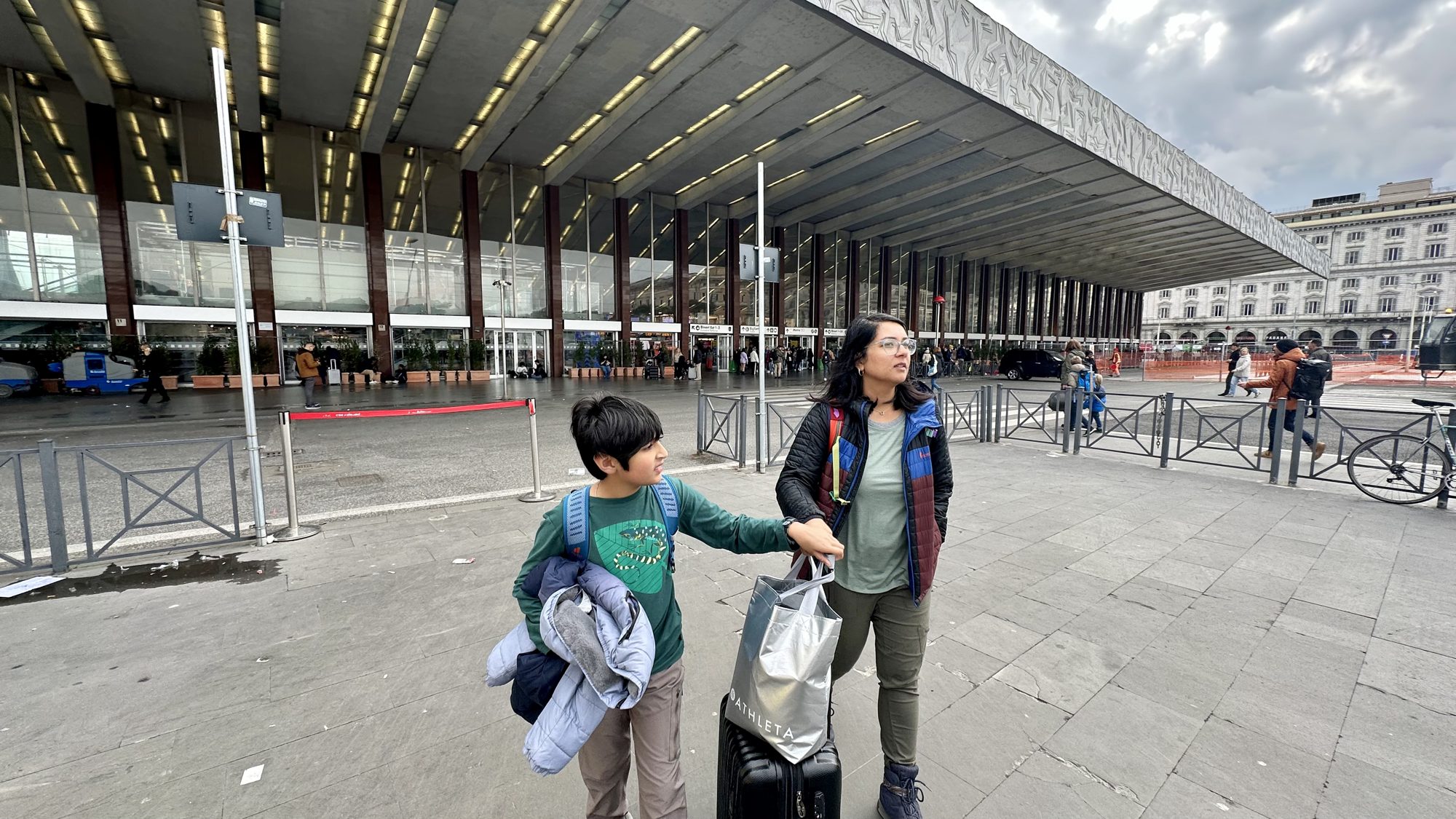 Boy and woman with their bags outside Roma Termini station
