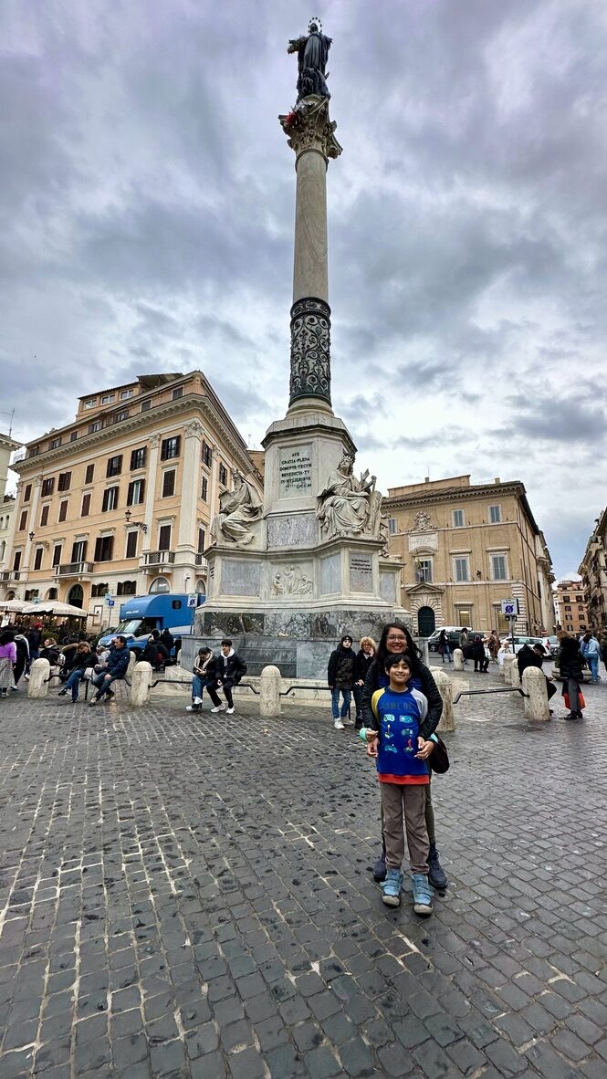 Woman and boy in a Rome square beneath a tall stone column