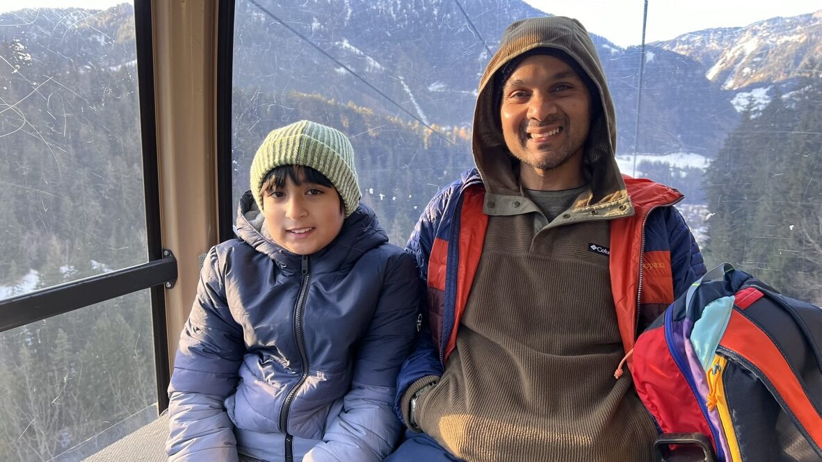 Boy and man smiling inside a cable car cabin, with snowy forest outside