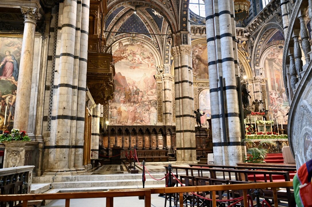 Inside Siena Cathedral, with striped marble columns and frescoed walls