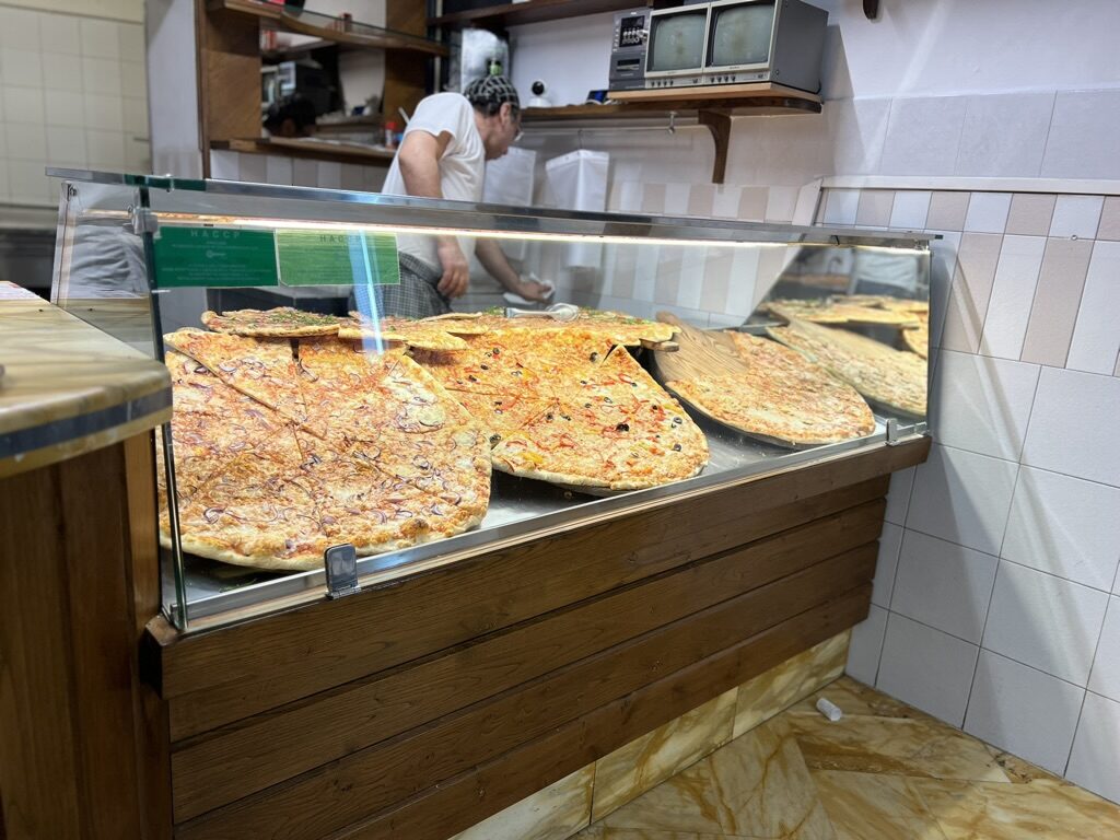 Long rectangular pizzas in a glass counter at a Siena pizzeria