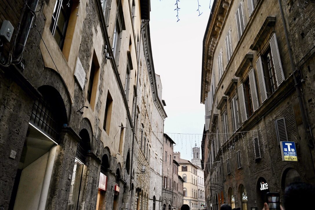 A narrow street of tall stone buildings in Siena’s old town