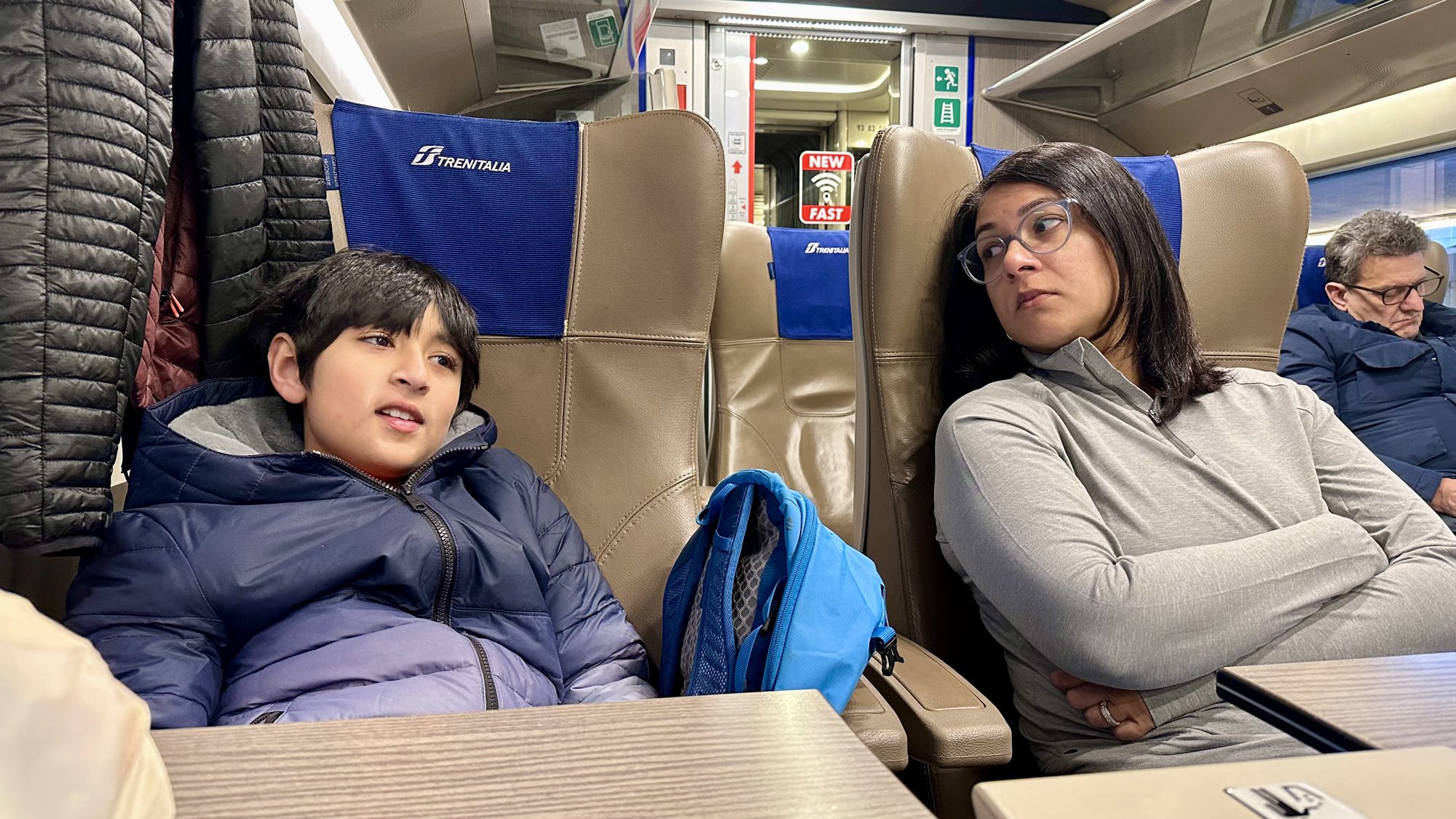 Boy and woman relaxing in business class train seats