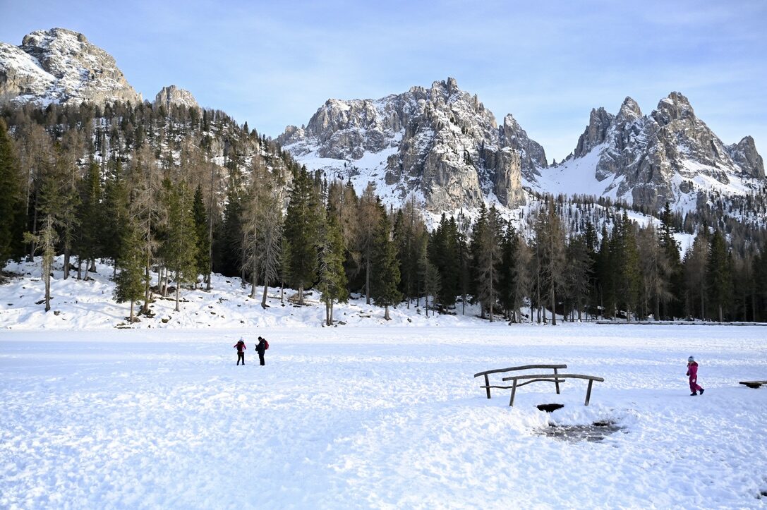 A snowy clearing with a picnic table and jagged peaks behind, near the road closure