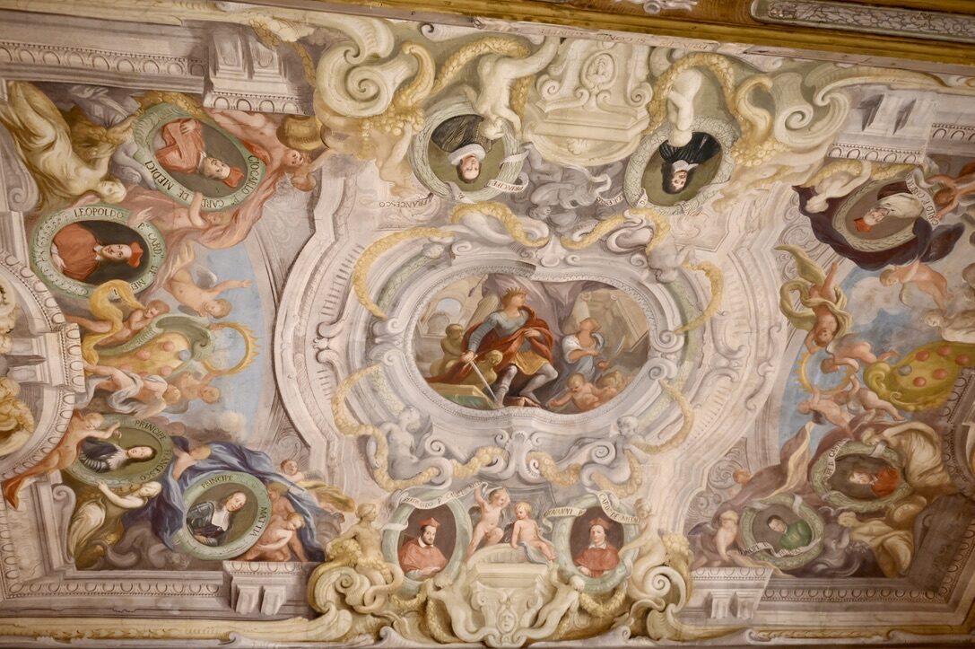 An ornate painted ceiling with portraits and gilded frames in the Uffizi