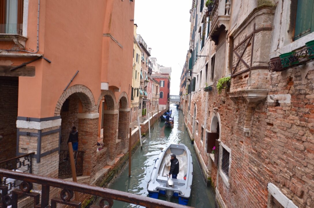 A narrow Venetian canal between old brick buildings, with a small boat