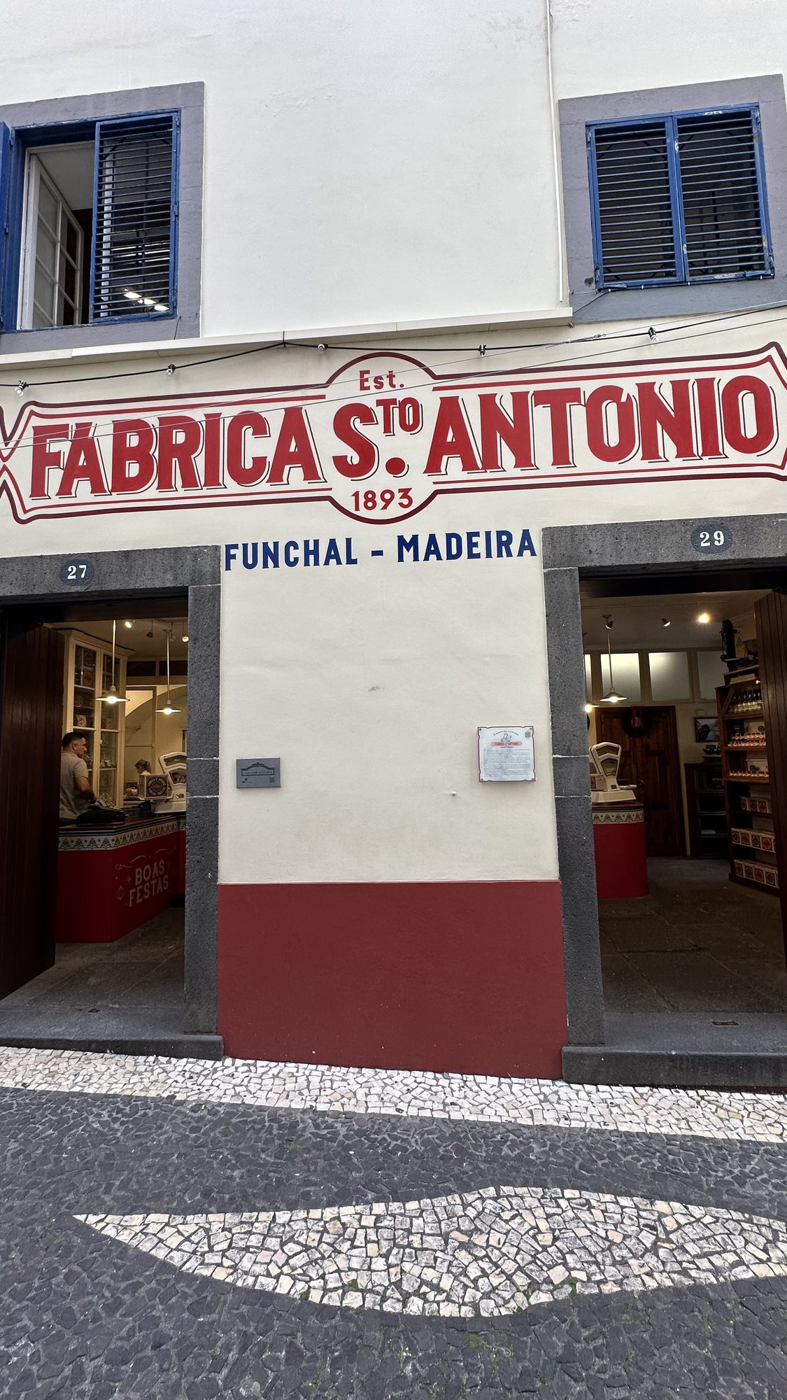 The white facade of Fábrica Santo António with its red painted sign, “Est. 1893, Funchal – Madeira”.