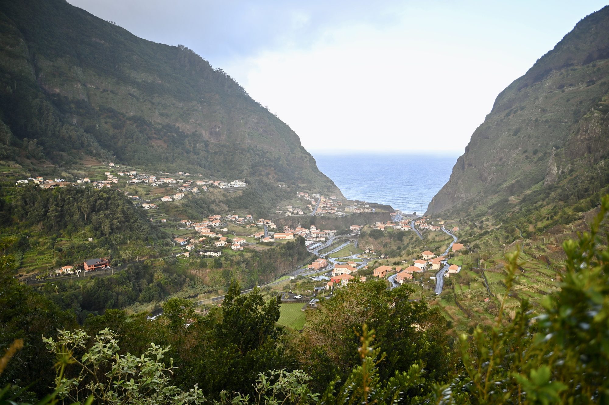 The town of São Vicente spread across the valley floor between two steep green mountainsides, opening to the sea.