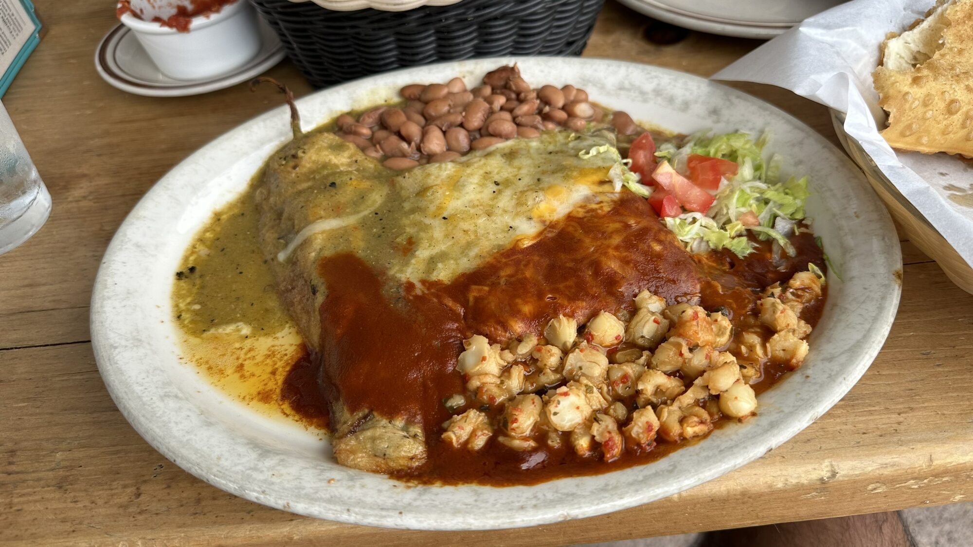 An enchilada and chile relleno combination plate with beans and posole