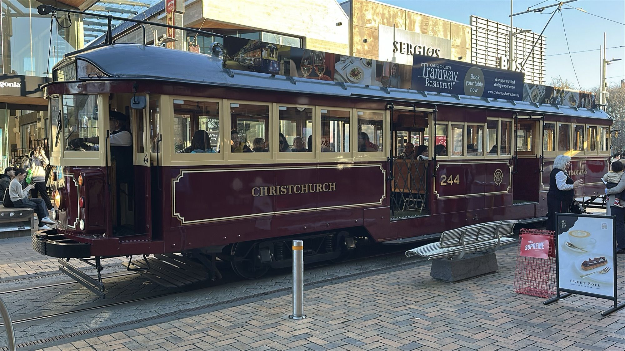 A maroon and cream heritage tram marked “Christchurch” stopped on a city street.