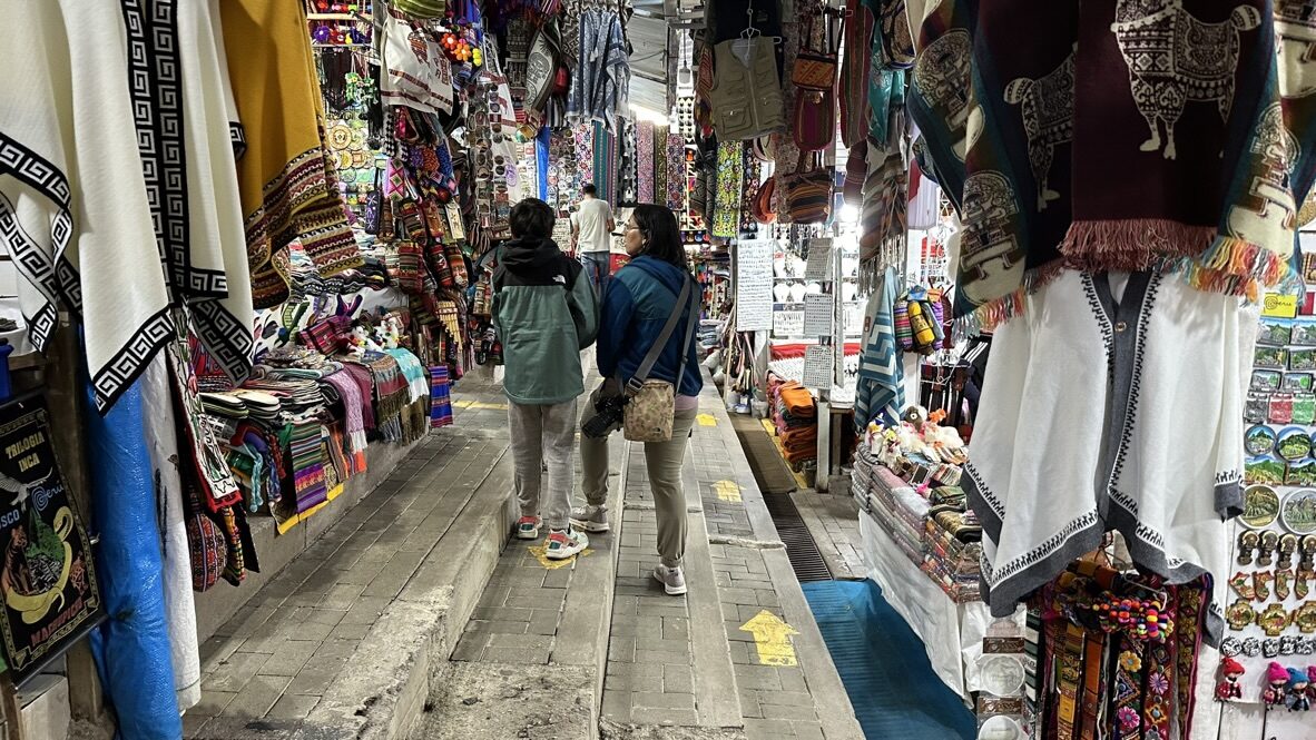Woman and boy walking through a market lined with colorful textiles