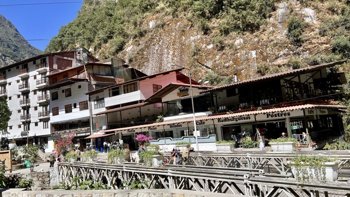The hotels and restaurants of Aguas Calientes below a steep green mountain