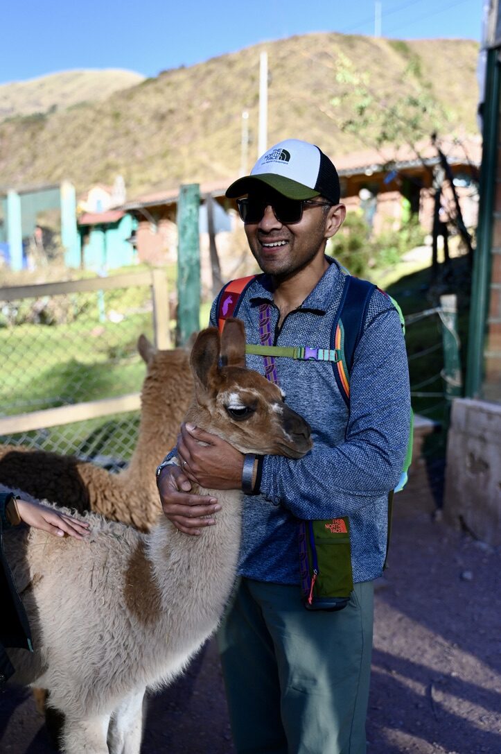Man smiling with a fluffy llama at the sanctuary