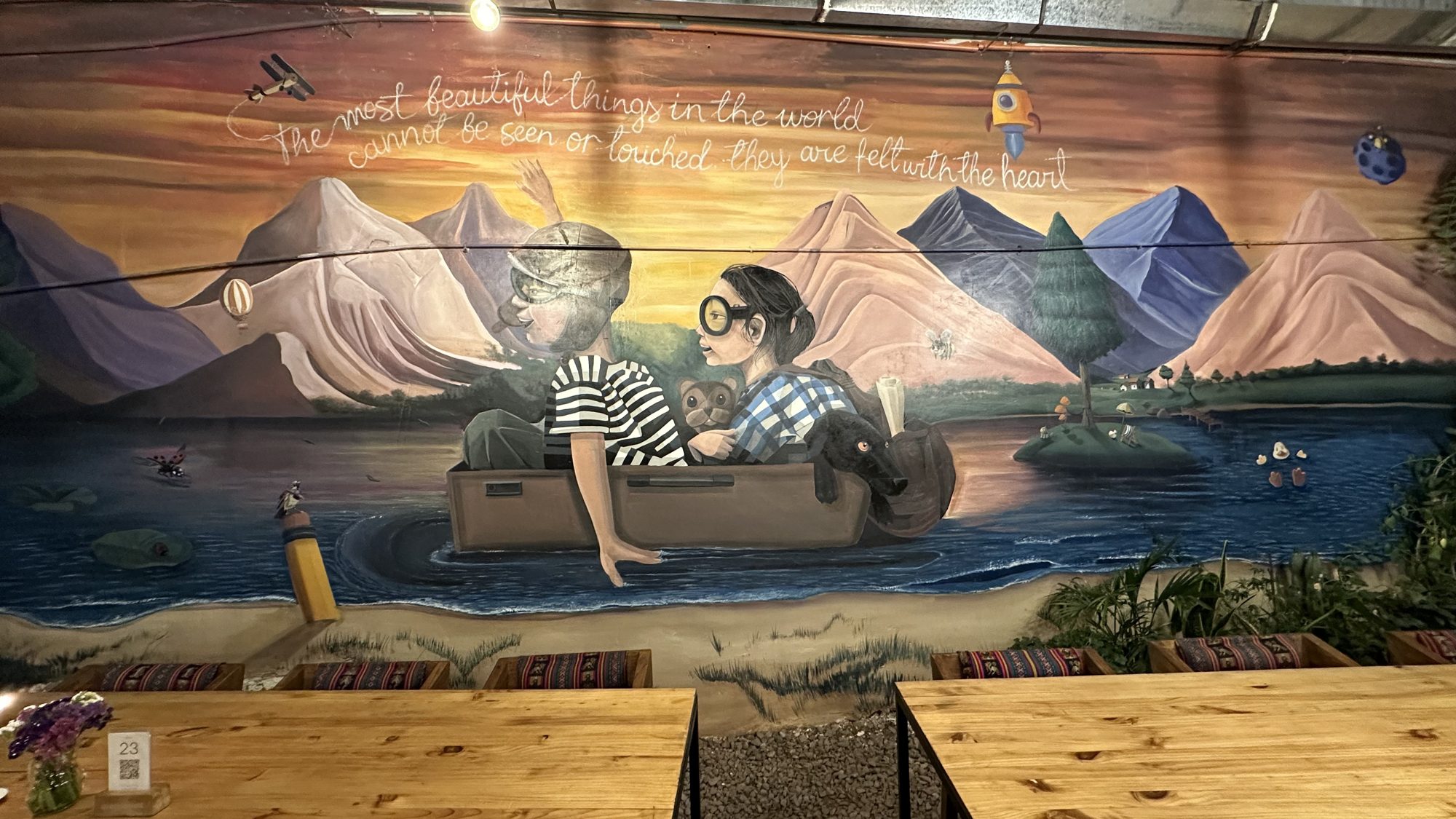 A painted mural of a family in a boat on a mountain lake, on the wall at Green Point