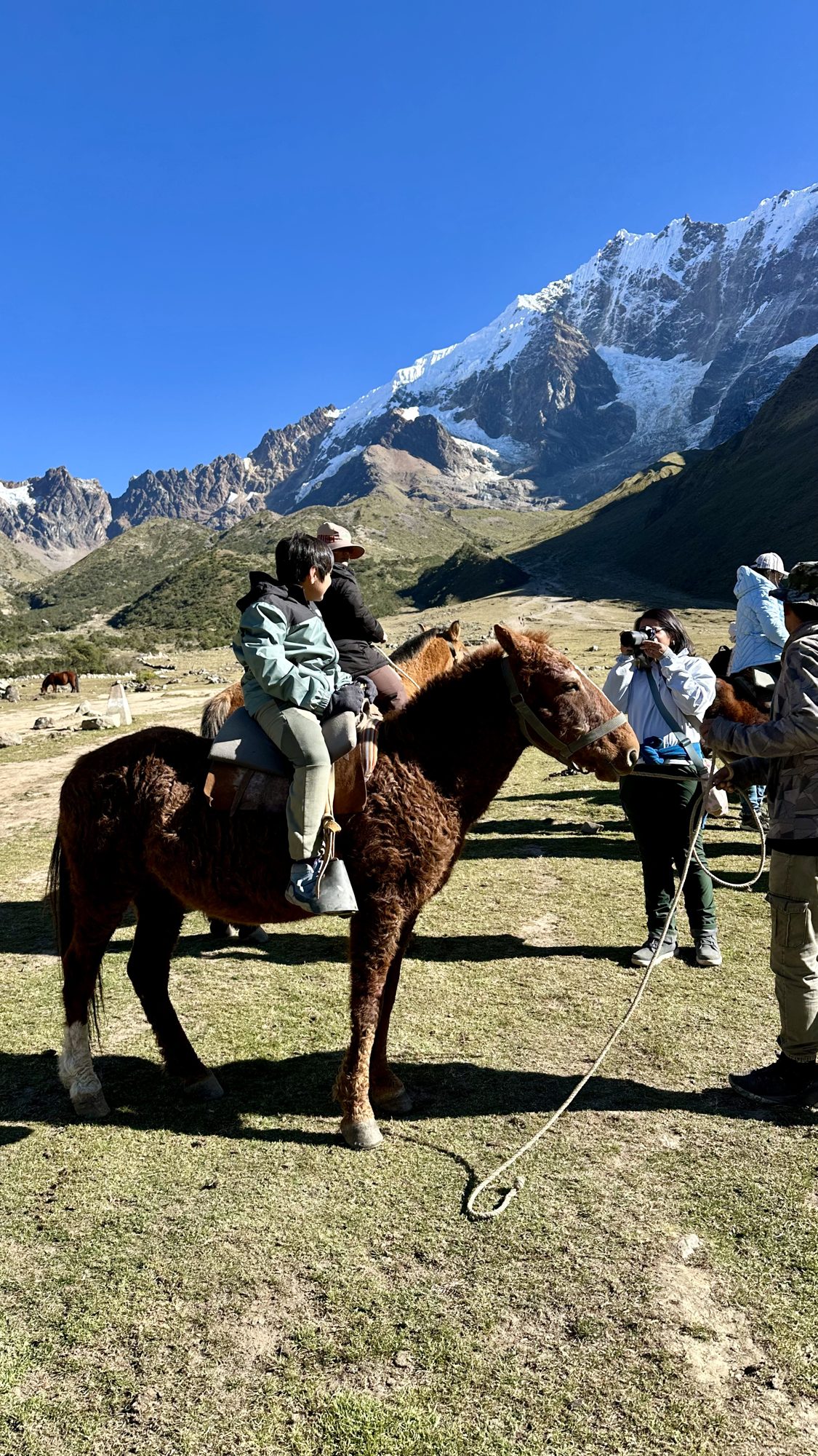 Boy on horseback with a guide, with snowy mountains behind