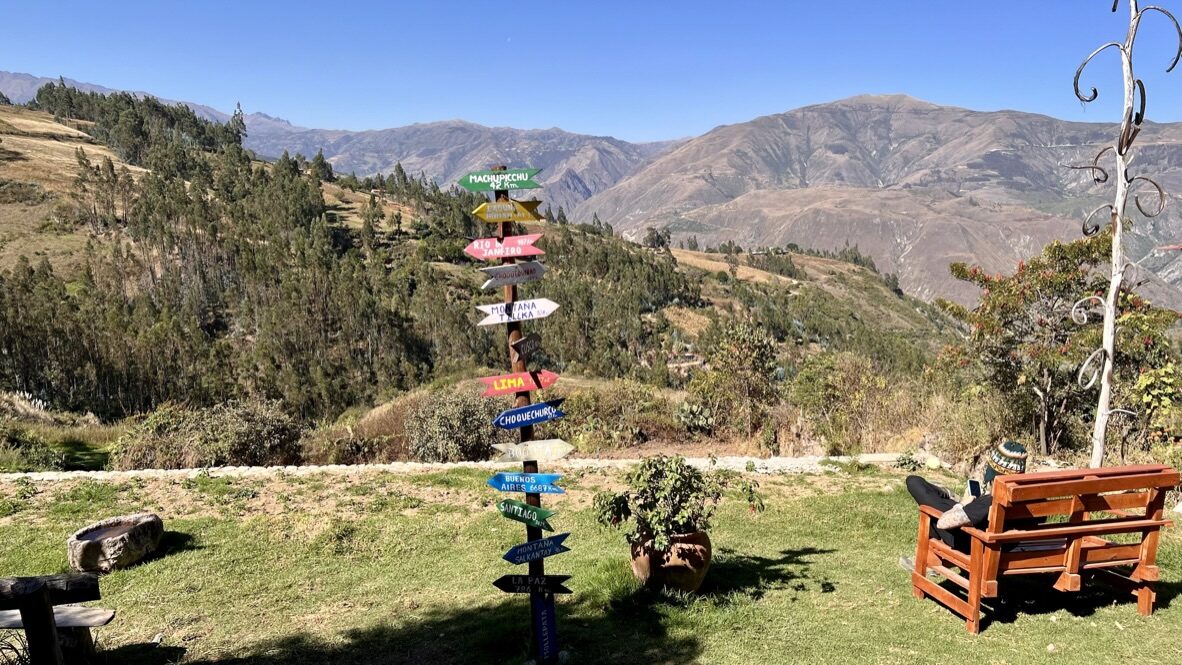 A garden with a colorful signpost and benches, looking over the hills