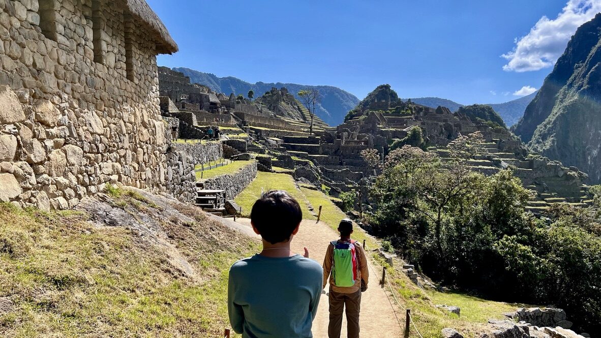 Boy and guide walking a path above the ruins