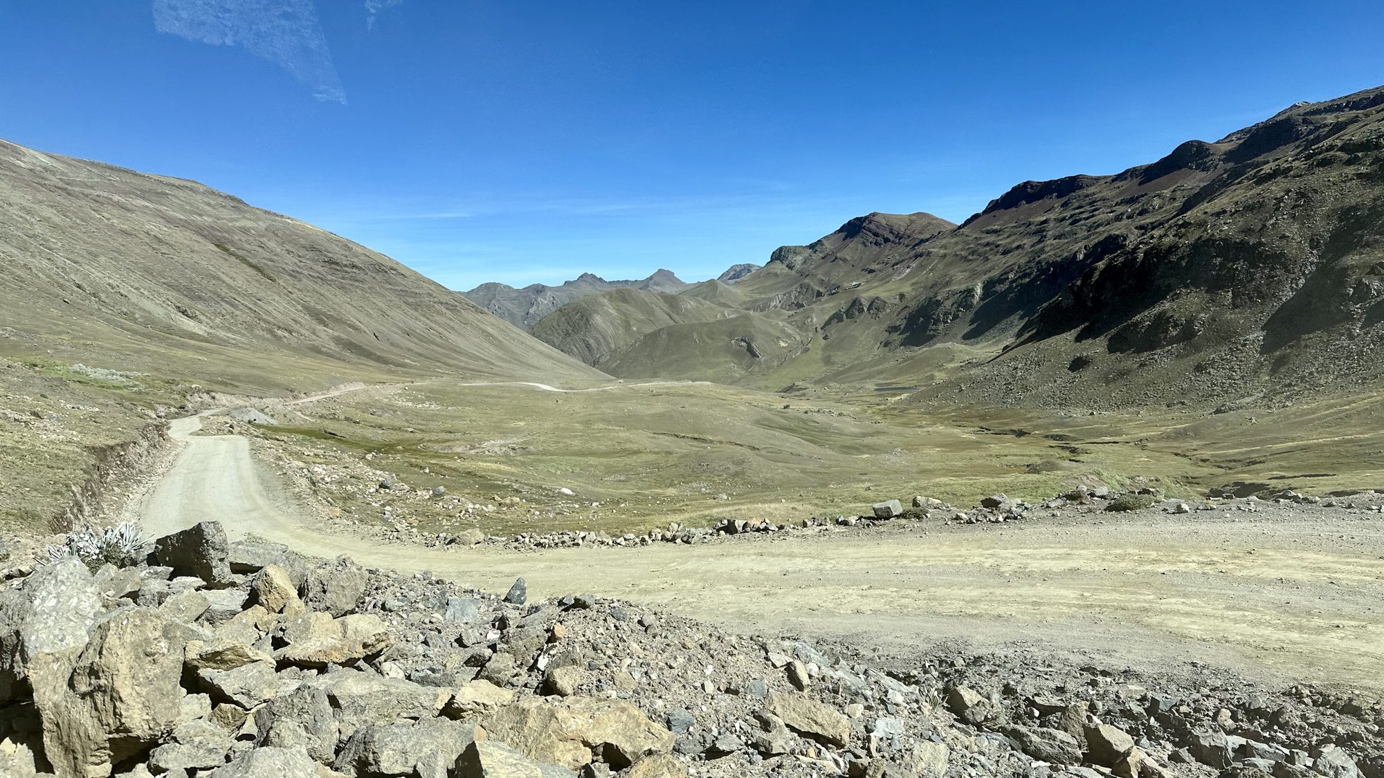 A dirt road winding through a wide, empty mountain valley