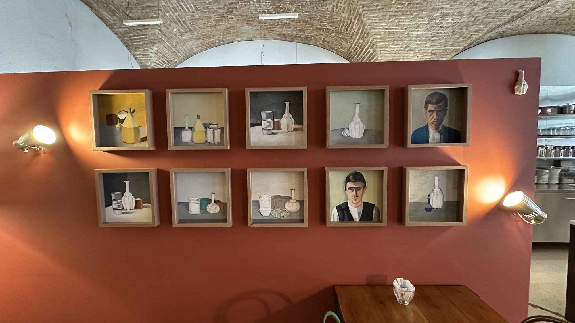 A warm orange wall at Landeau Chocolate hung with small framed paintings of bottles and portraits.